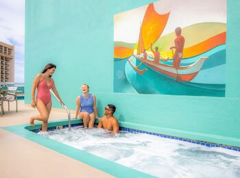 Three people are enjoying a small outdoor pool with a colorful mural of a boat and figures behind them.